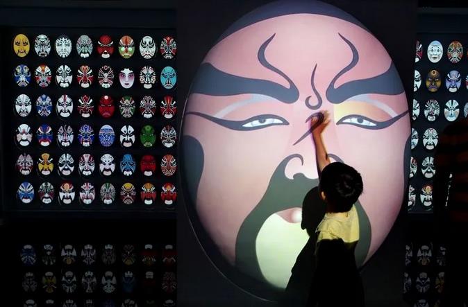 一位小观众在“上海非物质文化遗产保护实践展”的“数字非遗”展区了解京剧脸谱。 新华社记者 任珑 摄.jpg